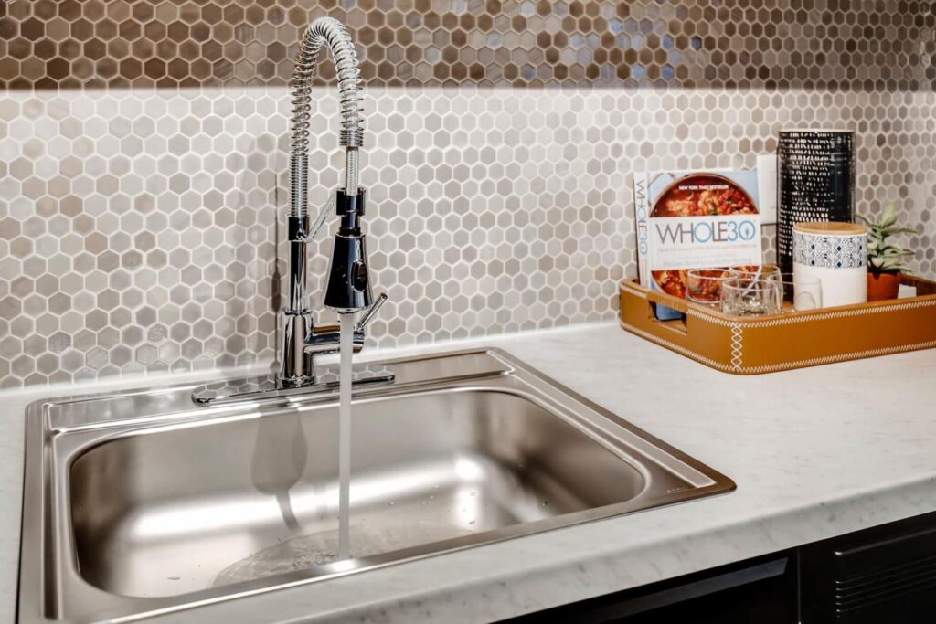 Stainless steel sink with tile backsplash at Copperwood Apartments in Jefferson County, CO